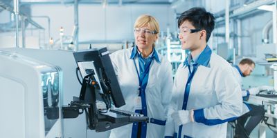 Male Asian engineer consulting with supervisor while looking at computer screen in scientific environment